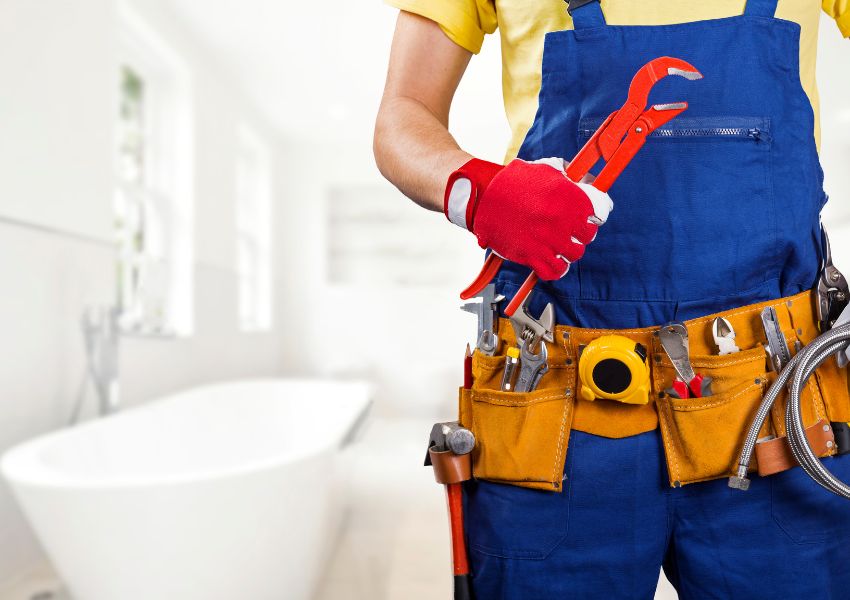 contractor holding a wrench and wearing a utility belt